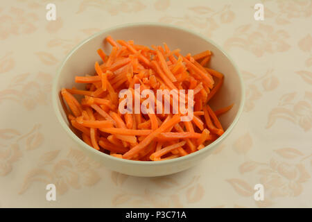 Découpez les carottes râpé dans un bol blanc comme ingrédient de la salade ou bien pour la cuisson que pour les gâteries pour chiens en bonne santé Banque D'Images