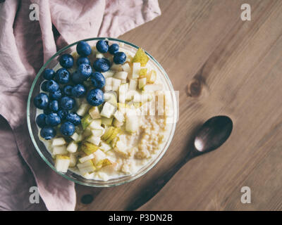 Vue de dessus du bol avec millet bouillie sur fond de table en bois. Porridge de millet bio avec Blueberry et de poire, l'espace de copie pour le texte. Soft focus DOF peu profondes, Banque D'Images