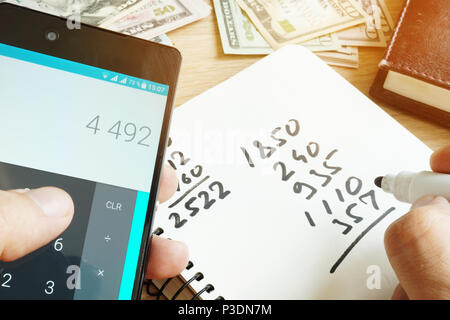 L'homme avec le smartphone le calcul pour les finances du foyer. Banque D'Images