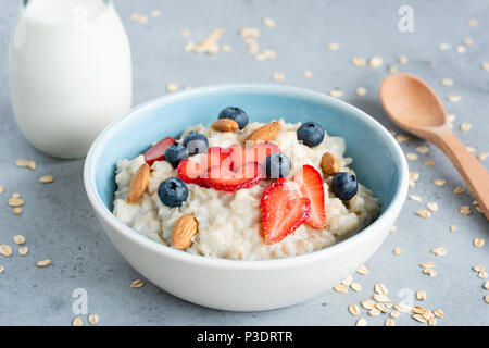 Bouillie d'avoine dans un bol bleu avec des baies et des noix. Bol de porridge d'avoine avec des fraises myrtilles et amandes. La saine alimentation, régimes, vegetari Banque D'Images