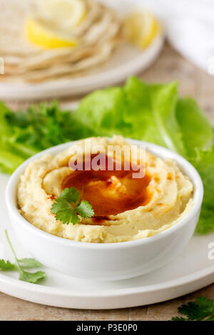 L'hoummos avec de l'huile d'olive et de paprika, servi avec pain pita, citron et de feuilles de laitue. Focus sélectif. Banque D'Images