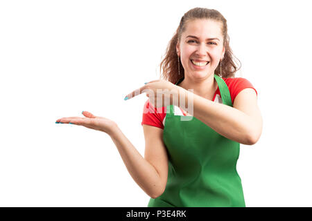 Jeune femme gaie supermarché employé de magasin holding objet invisible ou copie espace et en soulignant que la présentation concept isolated on white backgrou Banque D'Images