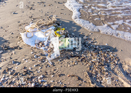 Une bouteille en plastique et autres déchets sur le sable, lavé par les vagues, un gros plan d'une plage polluée, Vejle, Danemark, juin 6, 2018 Banque D'Images