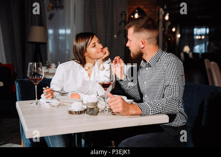 Jeune couple sur une date. Un homme d'une femme nourrit ses délicieux dessert. Libre dans le restaurant Banque D'Images