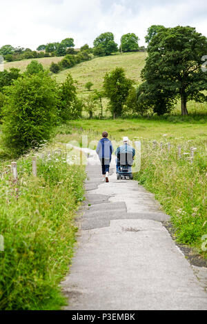 Une femme et un homme en fauteuil roulant sur un chemin qui est sur le lit d'un ancien réseau de chemin de fer, la vallée du collecteur Staffordshire England UK Banque D'Images