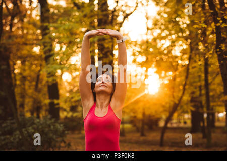 Woman performing exercice s'étendant dans la forêt Banque D'Images