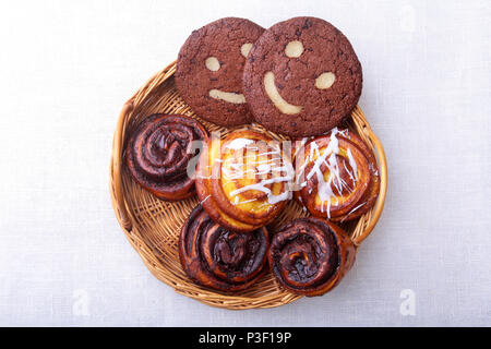 Des petits pains faits maison fraîchement préparés à la cannelle, biscuits dans un panier en osier. L'alimentation saine Snack-Concept. Copier l'espace. Banque D'Images