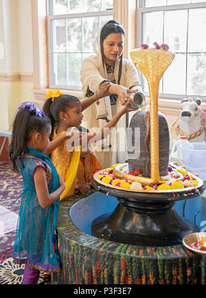 Un hindou adorateur et ses enfants faire une offrande au dieu Shiva Mandir Tulsi au sud de Richmond Hill, Queens, New York. Banque D'Images