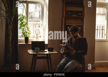 Man reading book in living room Banque D'Images