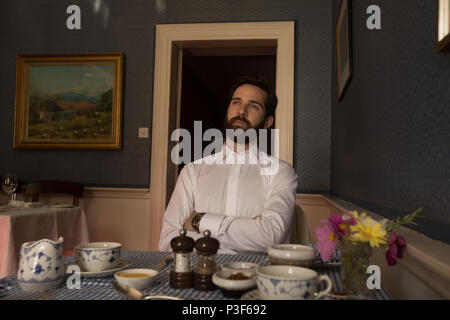 Thoughtful groom assis en face de repas sur le tableau Banque D'Images