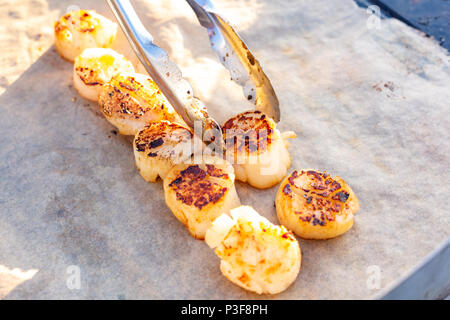 Chef professionnel Cuisiner les poissons sur un barbecue. Portionally morceaux de poisson frit sur du papier sulfurisé. La cuisson du poisson frit sur le grill Banque D'Images