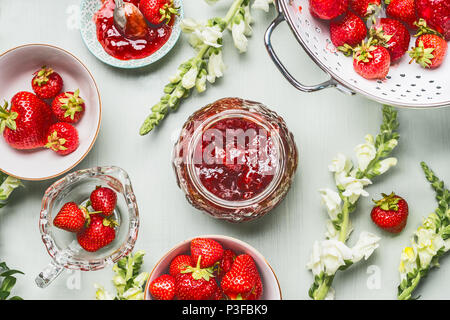 Les fraises de confiture dans un bocal en verre avec des fleurs d'été et les baies fraîches sur fond de table, vue du dessus. Concept fruits préserver Banque D'Images