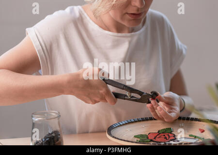 Poste de travail d'un maître de la mosaïque : mise en forme d'un élément de la mosaïque sur la table. Le maître établit sur une plaque en mosaïque fait main de maître Banque D'Images