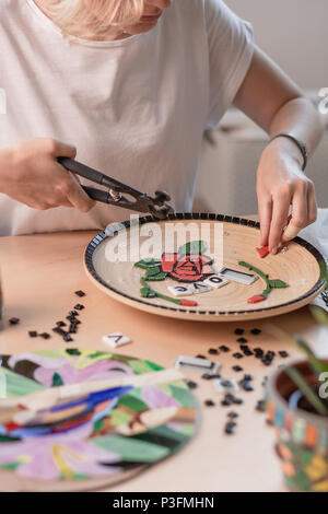 Poste de travail d'un maître de la mosaïque : mise en forme d'un élément de la mosaïque sur la table. Le maître établit sur une plaque en mosaïque fait main de maître Banque D'Images