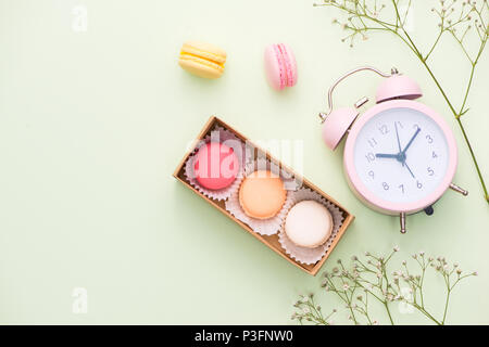 Macarons colorés et des fleurs rose avec boîte-cadeau sur table en bois. Macarons sucrés en boîte cadeau. Vue d'en haut Banque D'Images