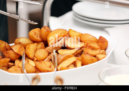 Serveur sert les pommes de terre cuites au four à la fête ou réception de mariage Banque D'Images