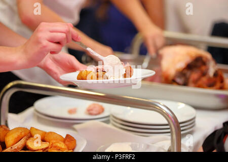 Serveur sert de viande rôtie et pommes de terre au four à la fête ou réception de mariage Banque D'Images