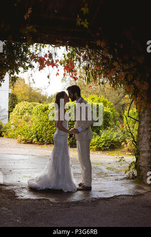 Mariée et le marié s'embrasser à l'entrée du jardin Banque D'Images