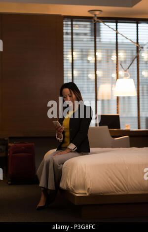 Businesswoman sitting on lit à l'aide de son téléphone portable Banque D'Images
