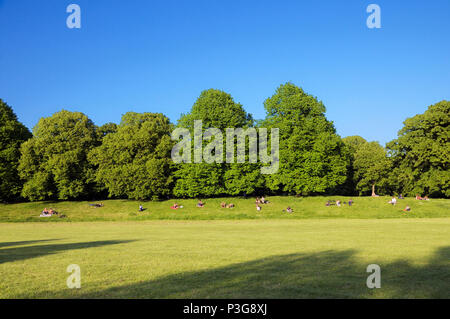 Les gens se détendre au soleil sur l'herbe des rives de Kensington Gardens, le Royal Borough de Kensington et Chelsea, Londres, Angleterre, Royaume-Uni Banque D'Images