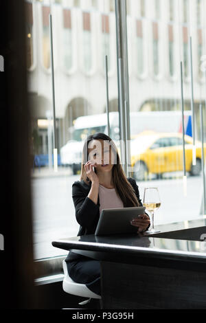 Businesswoman talking on phone while using her tablet Banque D'Images