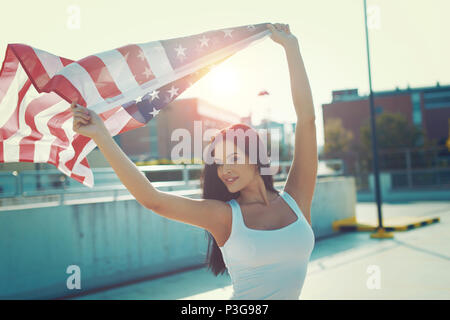 Jeune femme tenant un drapeau USA sur la tête à l'extérieur dans le coucher du soleil Banque D'Images