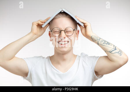 Sourire de l'homme blanc et cache son visage derrière un livre. Portrait Studio Banque D'Images