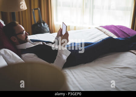 Businessman using digital tablet in bedroom Banque D'Images