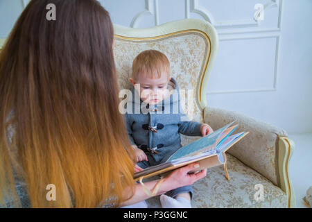 Jeune mère et son bébé assis sur le canapé et à la photobook togerher à la maison Banque D'Images