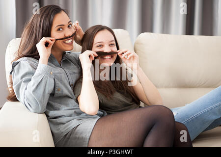 Deux soeurs jouant avec moustache sèche Banque D'Images