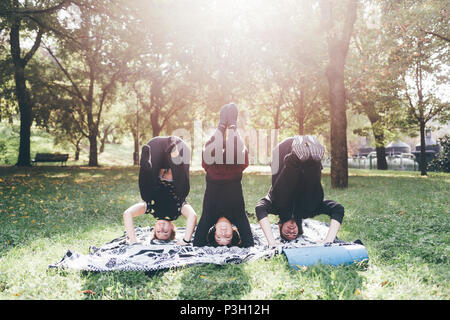 Jeune homme et les femmes en plein air qui s'étend dans un parc de la ville de sunny day - sportive, formation, bien-être concept Banque D'Images