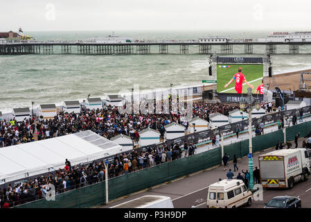 Brighton, East Sussex. 18 juin 2018. Les amateurs de football regarder Angleterre coupe du monde d'ouverture du match contre la Tunisie à Brighton's open air Luna Beach écran de cinéma sur le front de mer de Brighton. L'on voit ici, Harry Kane, capitaine de l'équipe de l'Angleterre célèbre l'objectif d'ouverture de leur campagne de coupe du monde en Russie, que le football fans célébrer devant le grand écran. Credit : Francesca Moore/Alamy Live News Banque D'Images