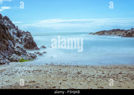 Une longue exposition de droit de la mer de lave autour des roches à Nobla Porth, conseil informatique sur l'île d'Anglesey. Banque D'Images