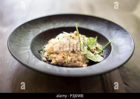 Vue rapprochée au risotto avec bijou en forme et le céleri levisticum sur une composition de tables en bois Banque D'Images