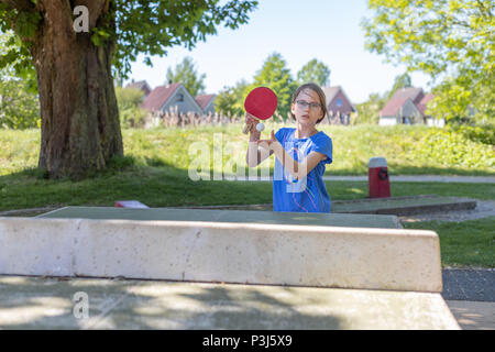 Une fillette de 9 ans joue au tennis de table sur une table de ping-pong. Elle joue le premier servi Banque D'Images