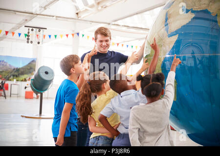 Les enfants de l'école montrant un globe géant dans un centre des sciences Banque D'Images