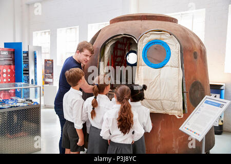 Les enfants et l'enseignant regarde une capsule spatiale dans un centre des sciences Banque D'Images