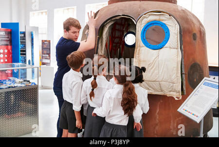 Les enfants et l'enseignant regarde une capsule spatiale dans un centre des sciences Banque D'Images