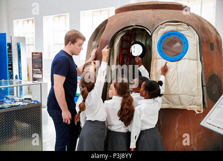 Les enfants et l'enseignant regarde une capsule spatiale dans un centre des sciences Banque D'Images