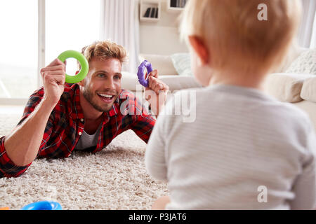 Jeune père lying on floor jouer avec petit garçon à la maison Banque D'Images