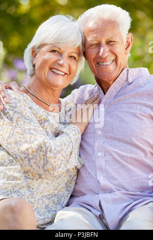 Happy senior couple sitting in the garden embracing Banque D'Images