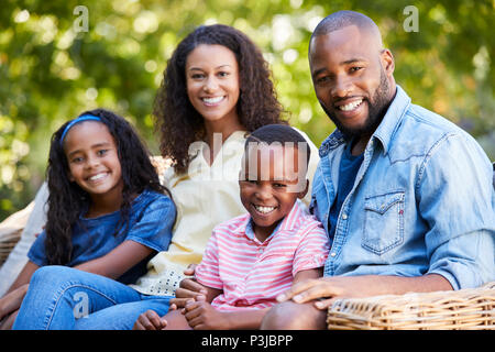 Mixed Race parents et enfants assis ensemble dans le jardin Banque D'Images