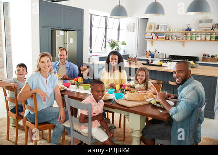 Deux familles de déjeuner ensemble à la maison à la recherche d'appareil photo Banque D'Images