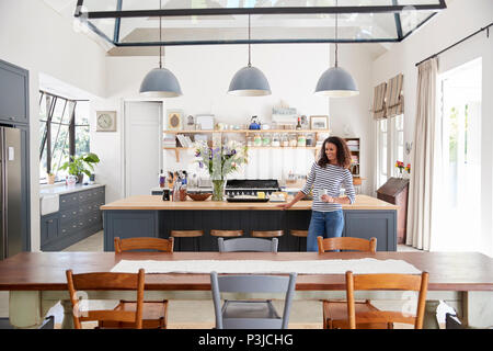 Mixed Race woman leaning on kitchen island en plan ouvert accueil Banque D'Images
