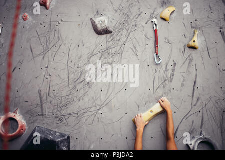 Climber mains tenant boulder en salle d'escalade artificielle, closeup shot Banque D'Images