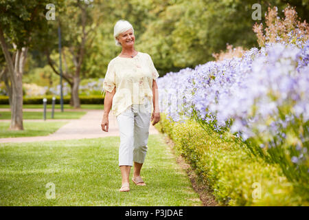 Senior Woman Enjoying Walk par Fleurs de Park Banque D'Images