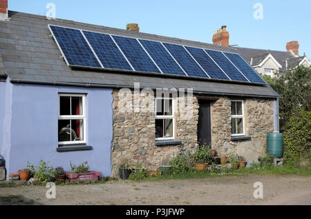 Cellules photovoltaïques panneaux solaires sur le toit d'une petite maison de campagne en pierre dans le village de Marloes Pembrokeshire West Wales, Royaume-Uni KATHY DEWITT Banque D'Images