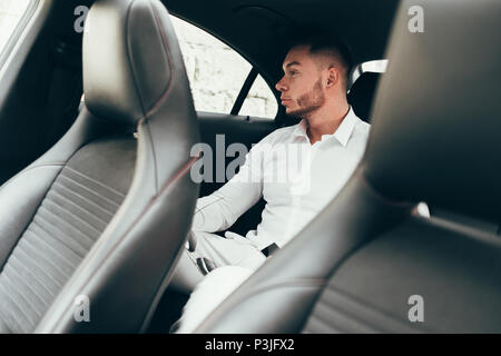 L'homme à l'écart tout en étant assis sur le siège arrière de voiture, businessman in taxi Banque D'Images