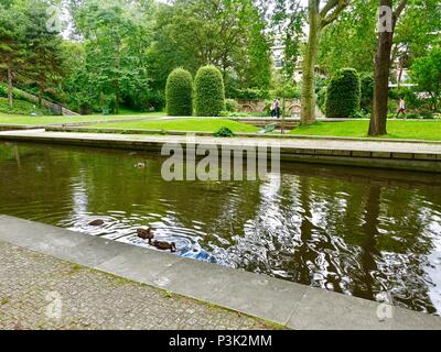 Les canards nagent dans l'étang tandis que les gens marchent dans le jardin des Philosophes, Parc Bercy, Paris, France Banque D'Images