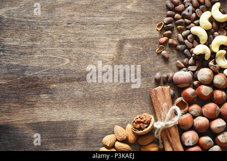 Les écrous différents sur une table en bois. Le cèdre, noix de cajou, noisettes, et une cuillère sur la table. Beaucoup de noix en coque sont et chistchenyh on a wooden background Banque D'Images